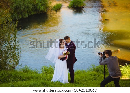 Photographer taking Pictures of the Bride and Groom near the river