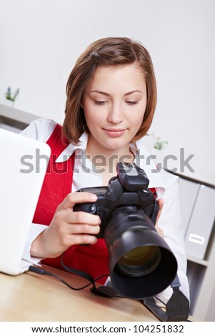 Female photographer in studio checking images on DSLR camera display