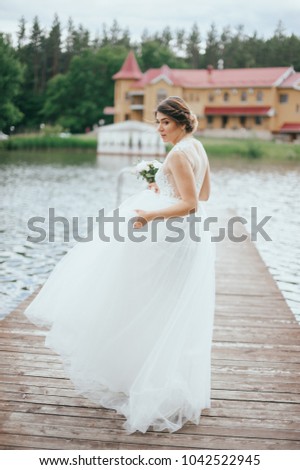 Portrait of a young beautiful bride on a background of a gorgeous view of the river and fields. Wedding day.