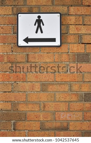 Sign on a brick wall with an arrow pointing to the men's washroom