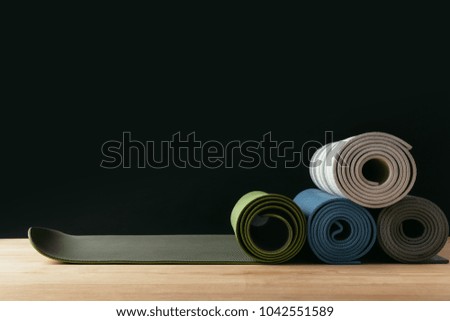 different colored rolled yoga mats on wooden table