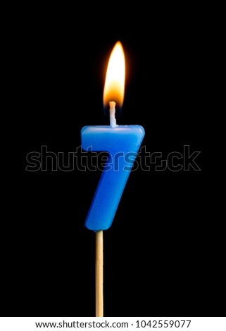Burning candle in the form of seven figures (numbers, dates) for cake isolated on black background. The concept of celebrating a birthday, anniversary, important date, holiday, table setting