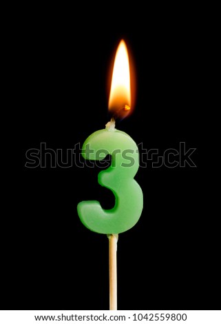 Burning candle in the form of three figures (numbers, dates) for cake isolated on black background. The concept of celebrating a birthday, anniversary, important date, holiday, table setting