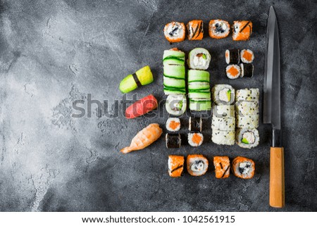 Japanese food concept with sushi, rolls and knife on dark background. Flat lay, Top view