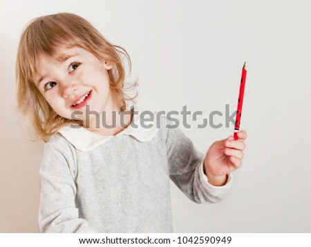 Portrait of happy baby girl beautiful holding a red pencil  on a white background