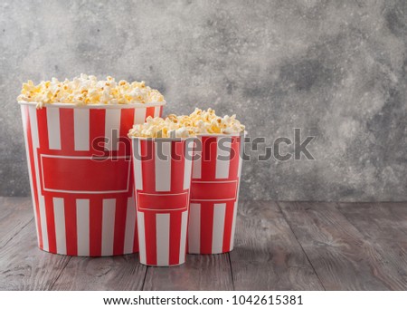 Popcorn in three striped buckets (red and white boxes) isolated on grey wooden table (background). Selective focus. Copy space. Nobody. Royalty-Free Stock Photo #1042615381