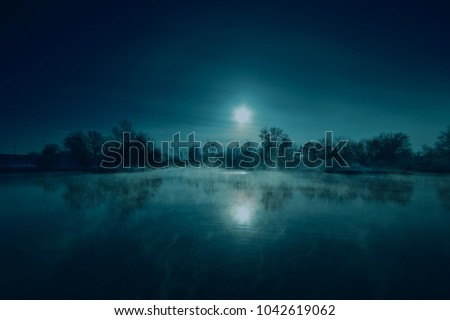 Night mystical scenery. Full moon over foggy river. Royalty-Free Stock Photo #1042619062