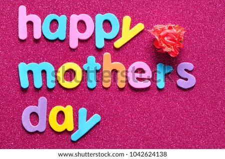 Happy mothers day on a pink background with an artificial rose