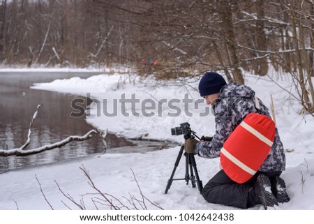 Woman Amateur photographer takes a winter landscape on the lake in the forest. copy space.