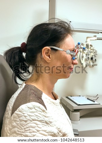 Woman being tested for new eyeglasses at an optometrist using equipment with interchangeable corrective lenses to measure her acuity