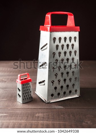 Two stainless graters little and big on wooden background