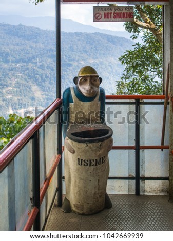A monkey in the uniform of the ancillary worker holds a trash can on which it is written "use me". Above this place the inscription "Thank you for not smoking".
