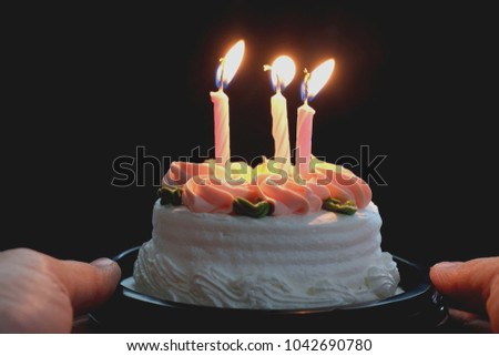 hand hold cake with candle on black background