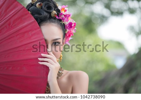 Beautiful Thai girl in traditional dress costume red umbrella, Thai Woman in Traditional Costume of Thailand. 