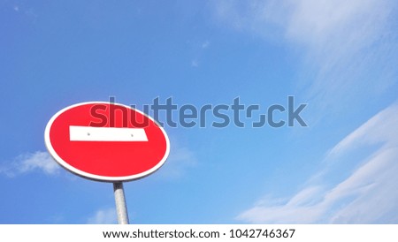 Round red road sign 'No entry' isolated on blue sky background with clouds                