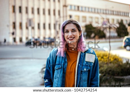 Picture of beautiful smiling rebellious woman with dyed hair at city street.