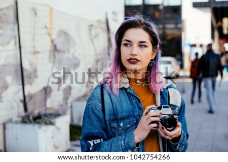 Beautiful young woman photographer holding a camera walking on the street.