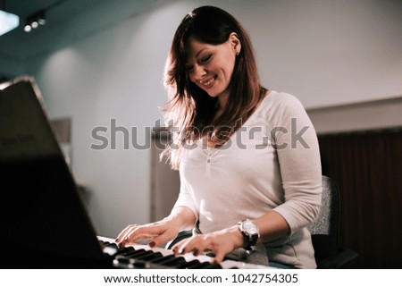 Charming young woman playing synthesizer piano.