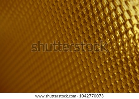 Plastic glass with a mosaic texture in the form of convex hexagons of golden color