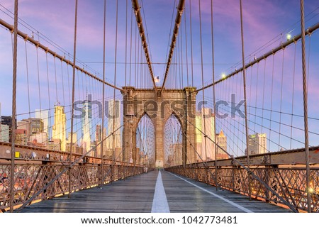 New York, New York on the Brooklyn Bridge Promenade facing Manhattan's skyline at dawn.