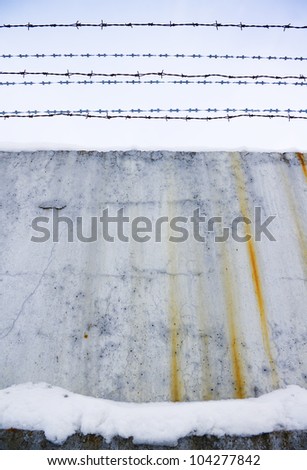 Concrete protection with a barbed wire covered with snow