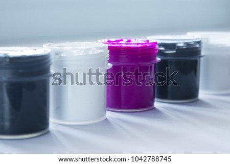 Black and white jars of paint with violet one, concept of White crown or outstanding thing or person