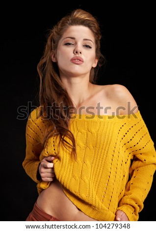 Portrait of a beautiful young female model posing against black background