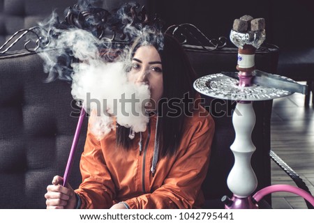 Girl in bright outfit smoking hookah  Royalty-Free Stock Photo #1042795441