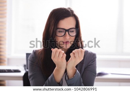 Close-up Of A Young Businesswoman Looking At Her Finger Nails In Office Royalty-Free Stock Photo #1042806991