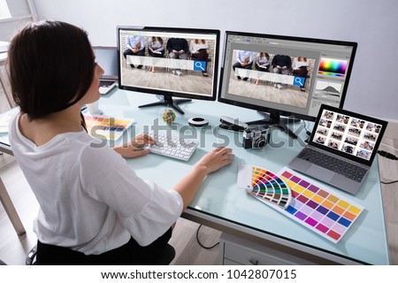 Close-up Of A Female Designer Working On Multiple Computer At Workplace Royalty-Free Stock Photo #1042807015