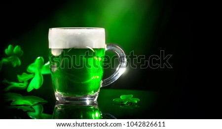 St. Patric's Day Green Beer pint over dark green background, decorated with shamrock leaves. Patric Day pub party, celebrating. Mug of Green beer close-up. Traditional Irish festival. Border art