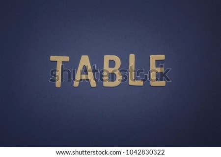 Table written with wooden letters on a blue background
