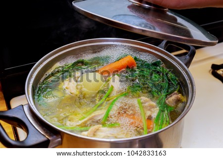 Ingredients for preparing chicken bone broth in a pot chicken, onions, celery root, carrots, parsley Royalty-Free Stock Photo #1042833163