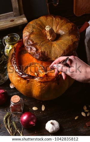 pumpkin cream soup poured into a baked pumpkin. still life in a rustic style. pumpkin seeds and spices next to the table.