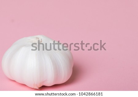 A clove of garlic against pink pastel background