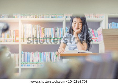 Portrait of clever Asian student reading and doing research in college library