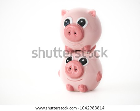 Funny close up photograph of two pink round pig ceramic salt and pepper shakers piggy backing or stacked on one another isolated on a white background with space around the animal shaped objects.