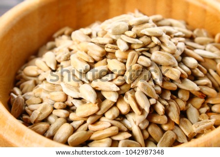 Black peeled sunflower seeds in a wooden bowl on a wooden table