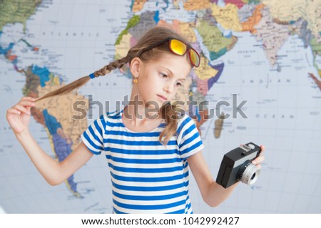 pretty little caucasian girl holding vintage camera and her pigtails on background of world map