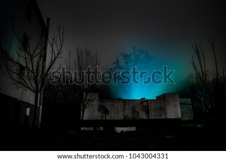 Old house with a Ghost in the forest at night or Abandoned Haunted Horror House in fog. Old mystic building in dead tree forest. Creepy house in the middle of a dark forest. Surreal lights