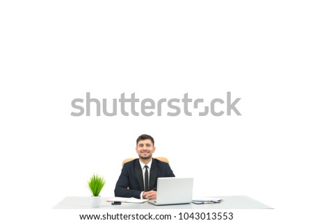 The happy businessman sitting at the desktop on the white background