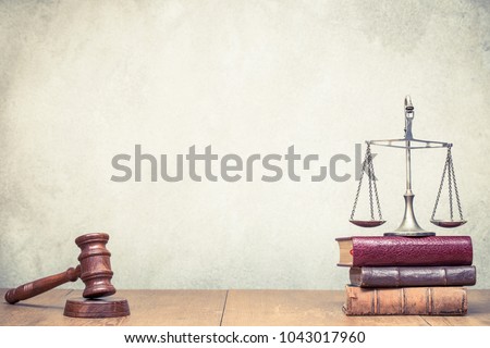 Wooden gavel, Vintage law scales and books on the desk front concrete wall background. Symbols of justice. Retro old style filtered photo