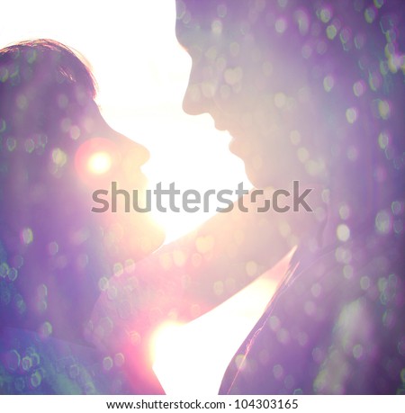 Young couple silhouette hugging and looking at each other outdoors at night neon city background