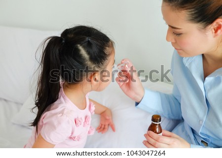 Little girl taking medicine Royalty-Free Stock Photo #1043047264