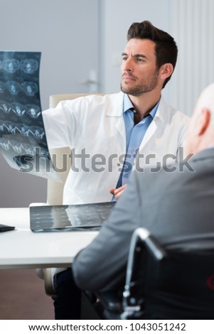 doctor looking at xrays during consultation with patient in wheelchair