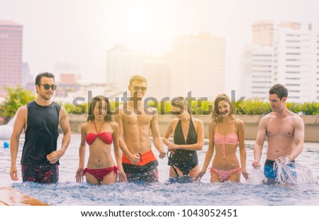 Multi-ethnic group of friends in a swimming pool - Young happy people having fun and enjoying summertime in pool party