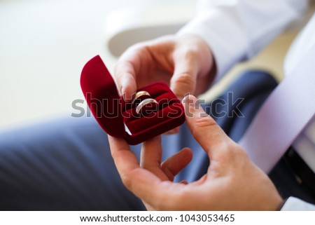 Picture of groom holding golden wedding rings