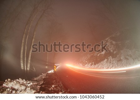 The traces of car lights on a snow-covered mountain road.