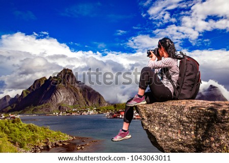 Nature photographer tourist with camera shoots while standing on top of the mountain. Beautiful Nature Norway Lofoten archipelago.
