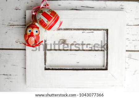 Easter vintage painted eggs on white wooden frame.Owl and gift decor on Easter egg.White rustic wall and empty frame.